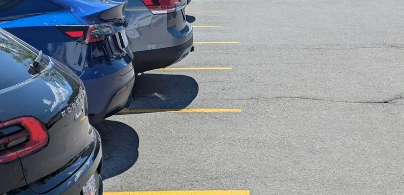 Parking lot with faded and barely visible stall lines, uneven spacing, and worn markings causing unclear parking layout and reduced visibility for drivers.